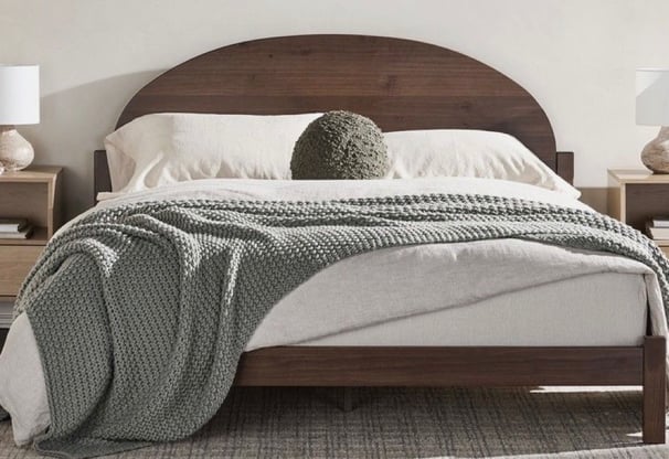 neutral brown bed frame with grey throw blanket and a accent pillow, with neutral paint, plaid rug