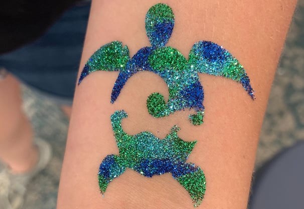 sea turtle glitter tattoo on skin with glitter colors of blue, aqua, and green