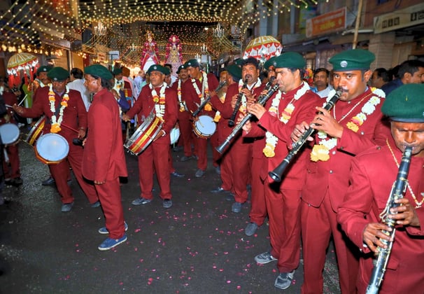 A team of Manohar Brass Band musicians aligned and playing clarinet, thap dhol, and nagara drum instruments.