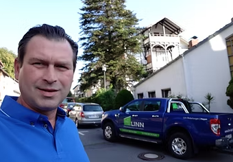 a man in a blue shirt is standing in front of a blue truck