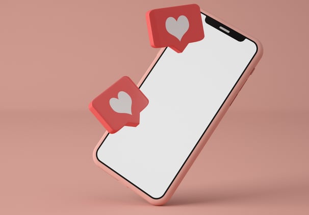 Image of a phone with like heart icons representing social media and design. Pink phone