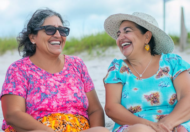 Dos mujeres mayores platicando y riendo en la playa 