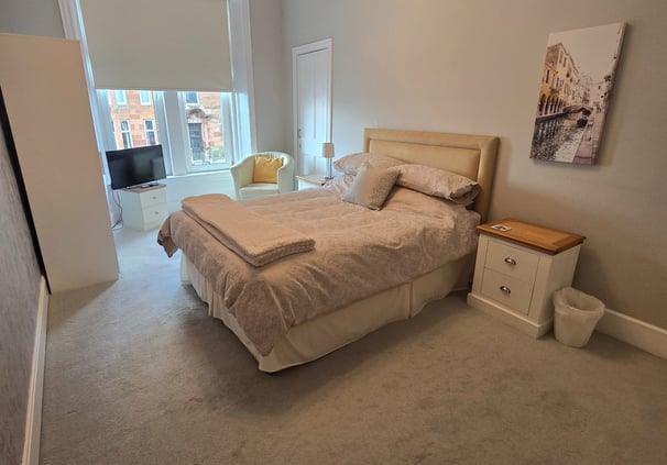 A large bedroom at Gourock Seaview Holiday Let with a kingsize bed and a chair