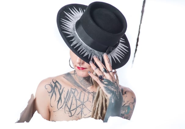 a woman with tattoos on her chest and a hat