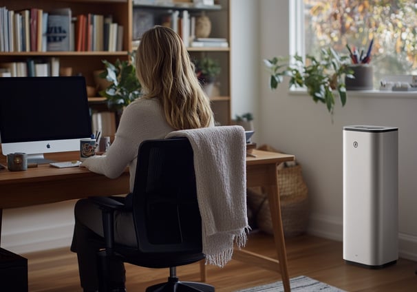 a woman sitting at a desk with a computer monitor and a computer monitor
