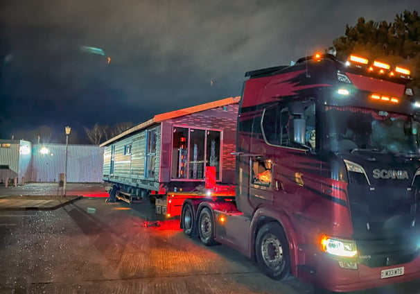 a truck with a trailer parked in front of a building. double lodge. eps panel. portable. affordable.