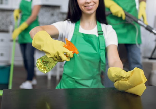 woman cleaning a kitchen surface with spray bottle