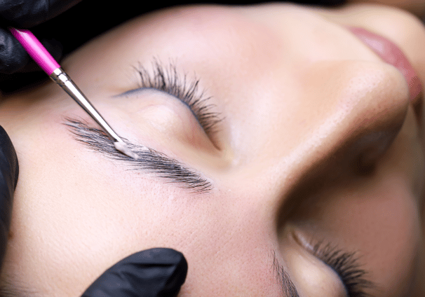 a woman getting her eyebrows laminated by a professional brow artist