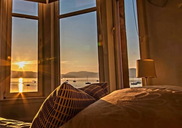 The bed at Gourock Seaview Holiday Let with a view of the sun setting over the water