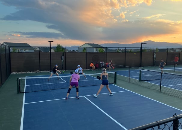 Adults playing competitive pickleball on outdoor courts during a pickleball coaching session.