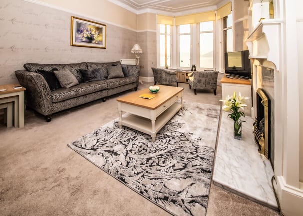 The spacious living room at Gourock Seaview Holiday Let with a couch, armchairs and a fireplace