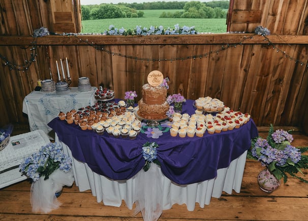 a table with a wedding cake and cupcakes on it