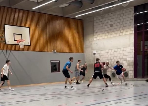 alt="Jugendliches Basketballteam beim Training auf dem Feld."