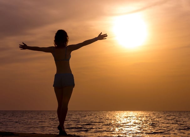 femme libre et heureuse qui regarde l'horizon en levant les bras