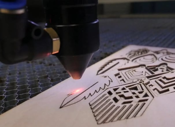 Una máquina de grabado láser en el proceso de cortar de una placa de madera