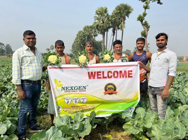 a group of men standing in a field with a welcome sign