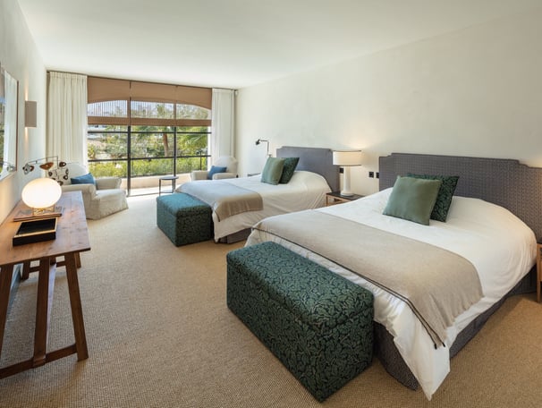 Spacious guest bedroom at Villa La Gratitud with two large beds, garden views, and cozy seating area