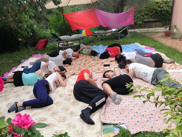 a group of people sitting on a blanket on a blanket, rilassamento, classe bioenergetica