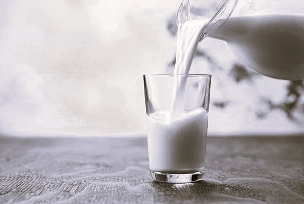 a pitcher of milk being poured into a glass