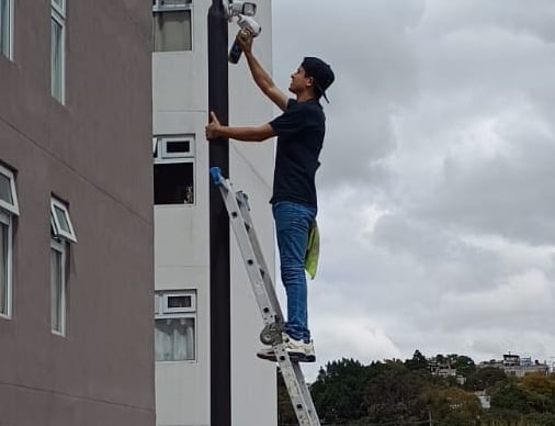 técnico realizando mantenimiento a cámaras de seguridad de un condominio