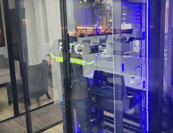 Técnico trabajando dentro de cuarto de servidores con gabinete iluminado.