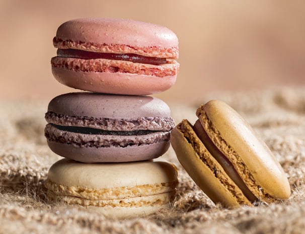 4 macarons dont trois empilés sur toile de jute et fond marron clair