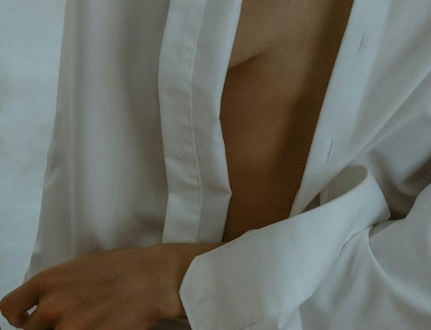 Minimalist close-up of a woman in an open white shirt — soft, sensual morning moment