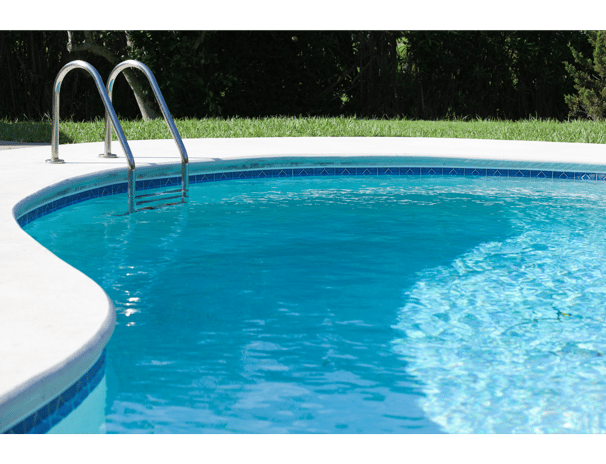 Medium shot of a kidney-shaped clear-blue pool with ladder