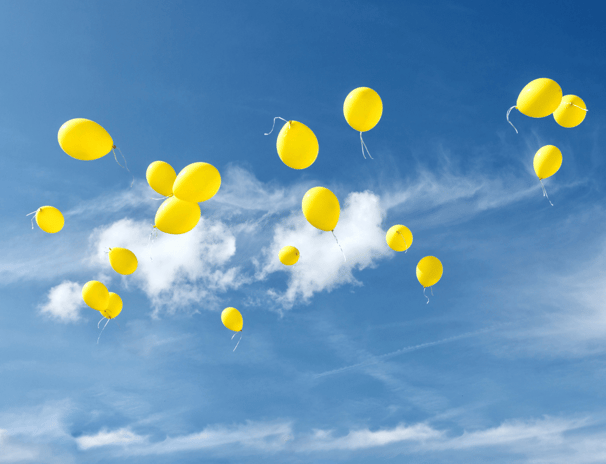 Cielo azzurro limpido con palloncini gialli che volano via, simbolo del lasciare andare, di libertà