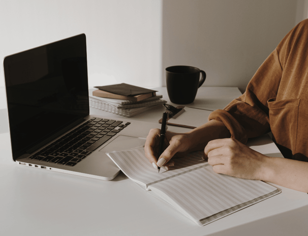 Persona che scrive su un quaderno in modo riflessivo, simbolo di scrittura CREATIVA, journaling