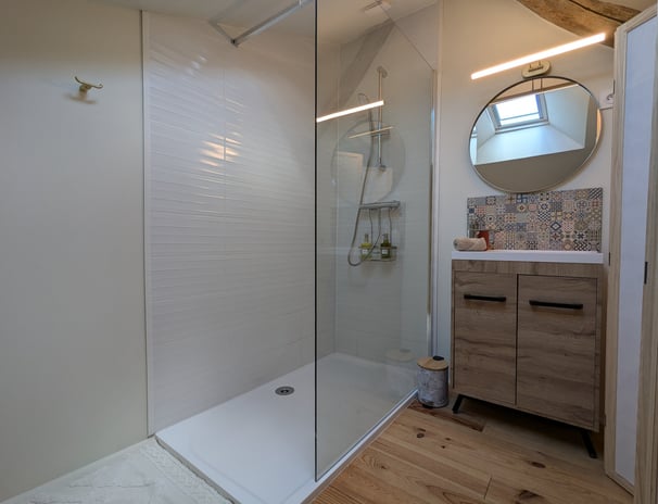 a bathroom with a shower and a wooden vanity