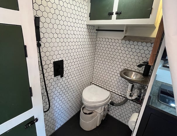 tiled shower inside epic overlanding rig, composting toilet, small sink and rainfall showerhead