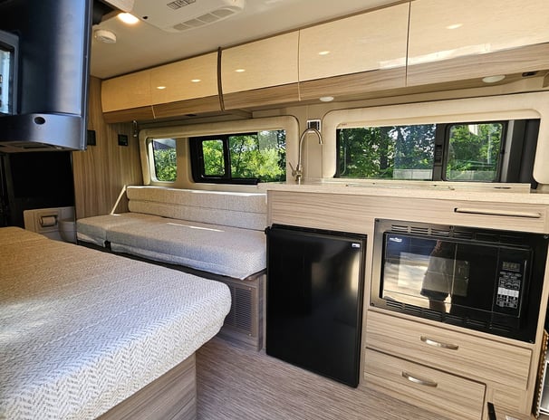 Sleeping area and kitchen of barely used 2023 Entegra Coach Ethos 20T Class B RV for sale.