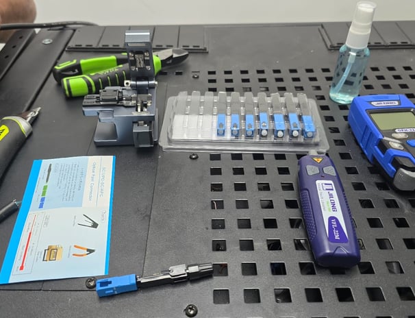 Mesa de trabajo con herramientas para instalación de conectores de fibra óptica SC/APC y equipos de medición óptica.
