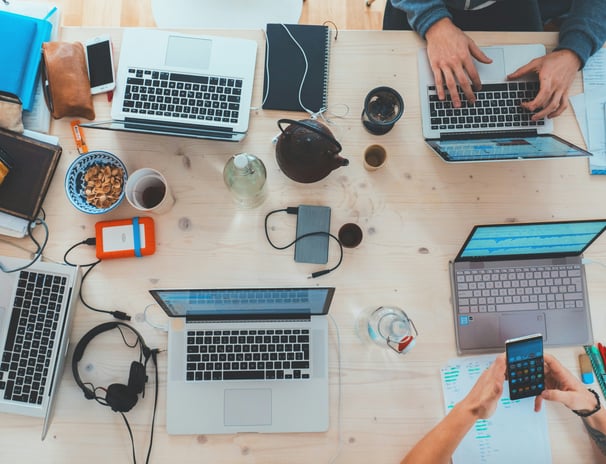 a group of people sitting at a table with laptops and cell phones
