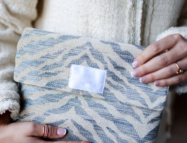 Trousse de toilette ÉTOFÉ en tissu d’ameublement revalorisé beige et bleu, tenue à la main