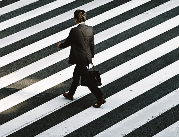 a man in a suit and tie walking across a crosswalk