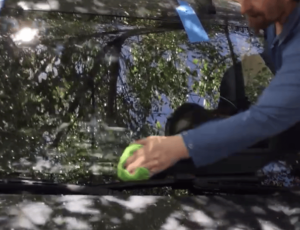 A Technician is finishing a windshield replacement and wiping down the windshield.