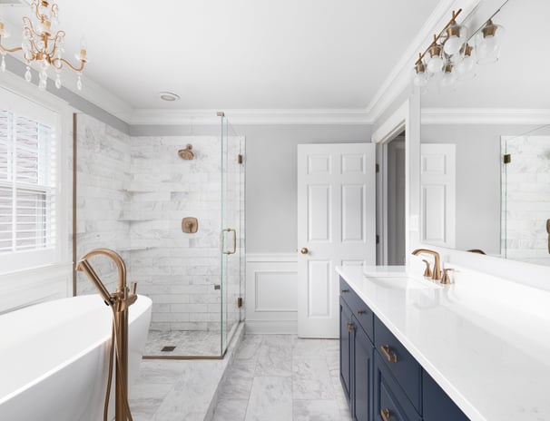 Luxury bathroom remodel with marble tile, navy vanity, and gold fixtures in London, Ontario.