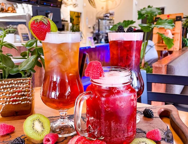 a table with a variety of ice teas and flavored lemonade