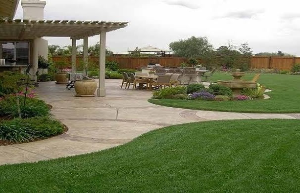 A vibrant garden landscape features lush green and red foliage. In the foreground, there is a structure covered with netting