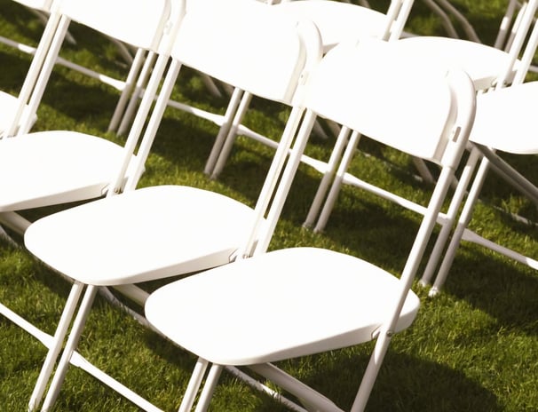 Sillas blancas plegables para eventos al aire libre en el paso