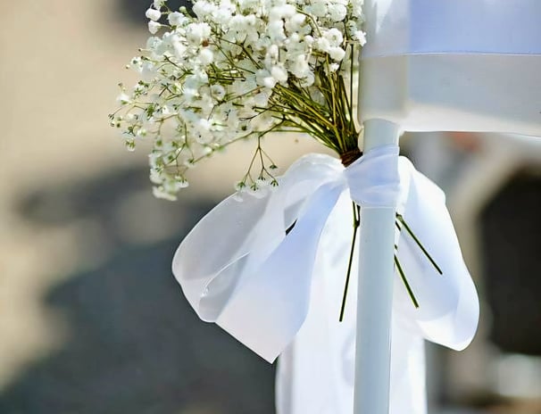 Silla para boda decorada con un liston blanco y flores