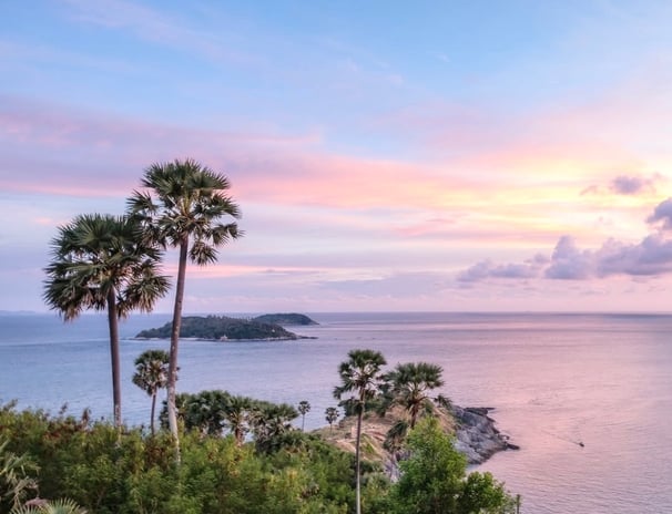 a lookout view from Phuket Thailand with Palm trees and islands at sunset