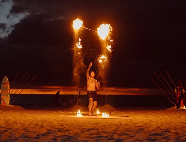 a man throws flaming torches in the air on a beach in Bang Tao Thailand