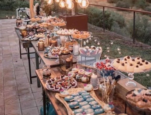 Buffet sucré en plein air avec desserts maison, vaisselle vintage et décoration lumineuse pour une f
