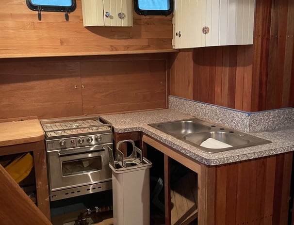 a kitchen with a sink and a gimbled stove, wood walls and sliding cabinet door