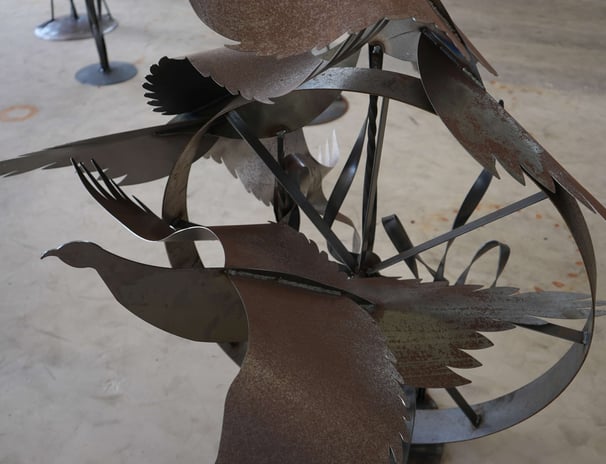 a metal sculpture of a bird on a wheel