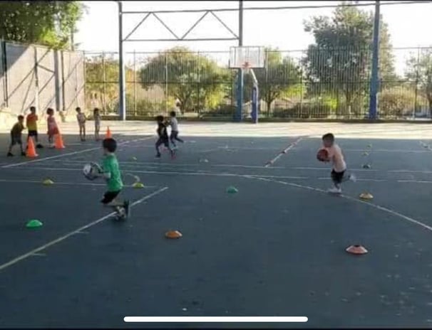 קבוצת ילדים צעירים משחקים כדורסל במגרש, בעת פעילות ספורטיבית של יום הולדת