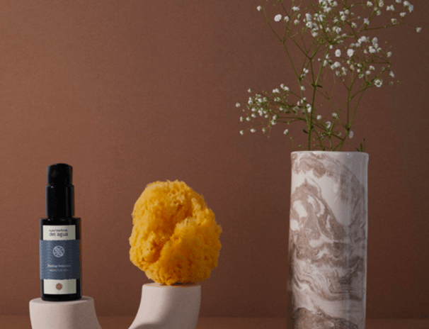 a vase with a flower in it and a bottle of essential oils